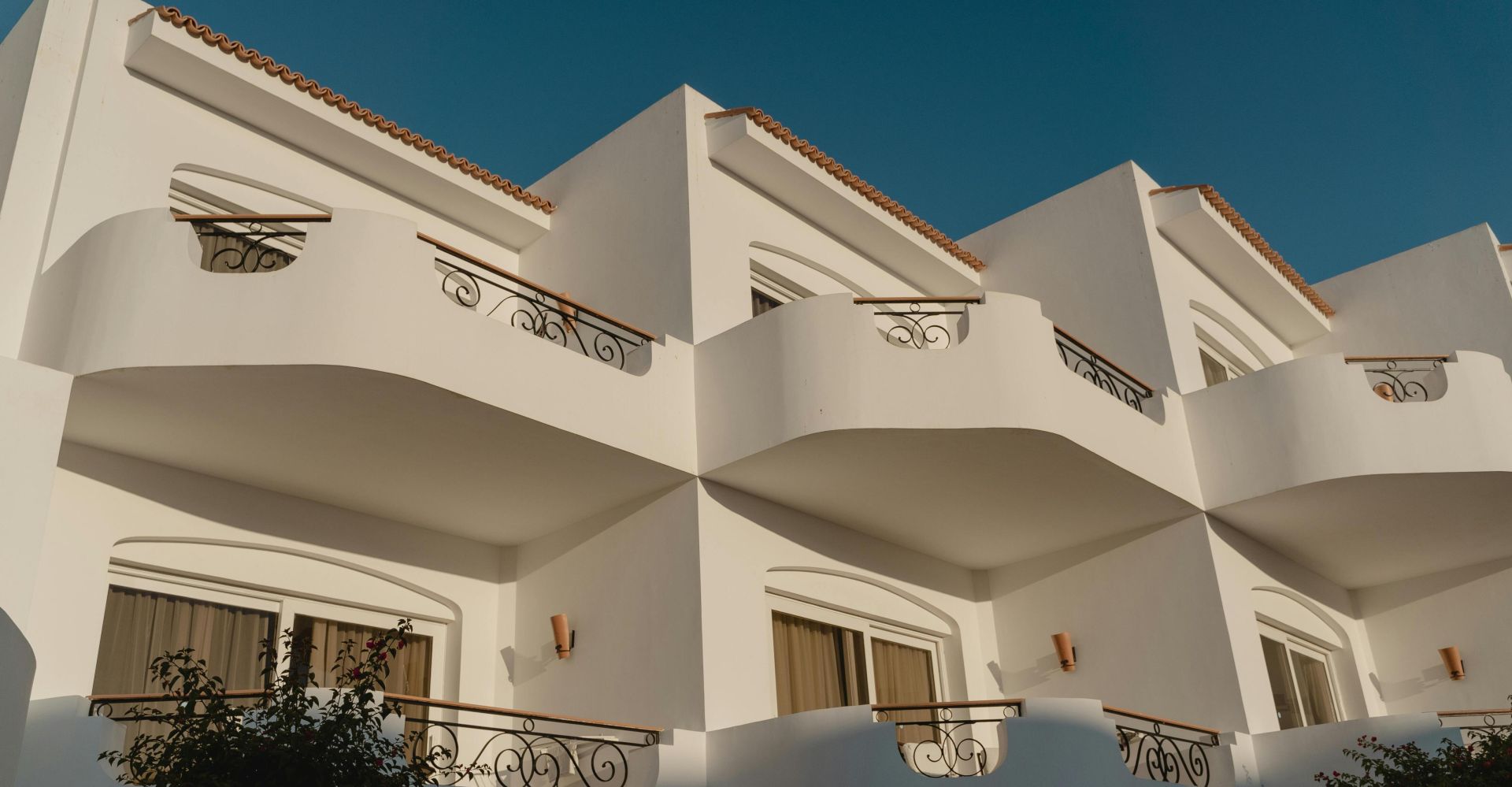 Elegant white Mediterranean building with ornate balconies under a clear blue sky.