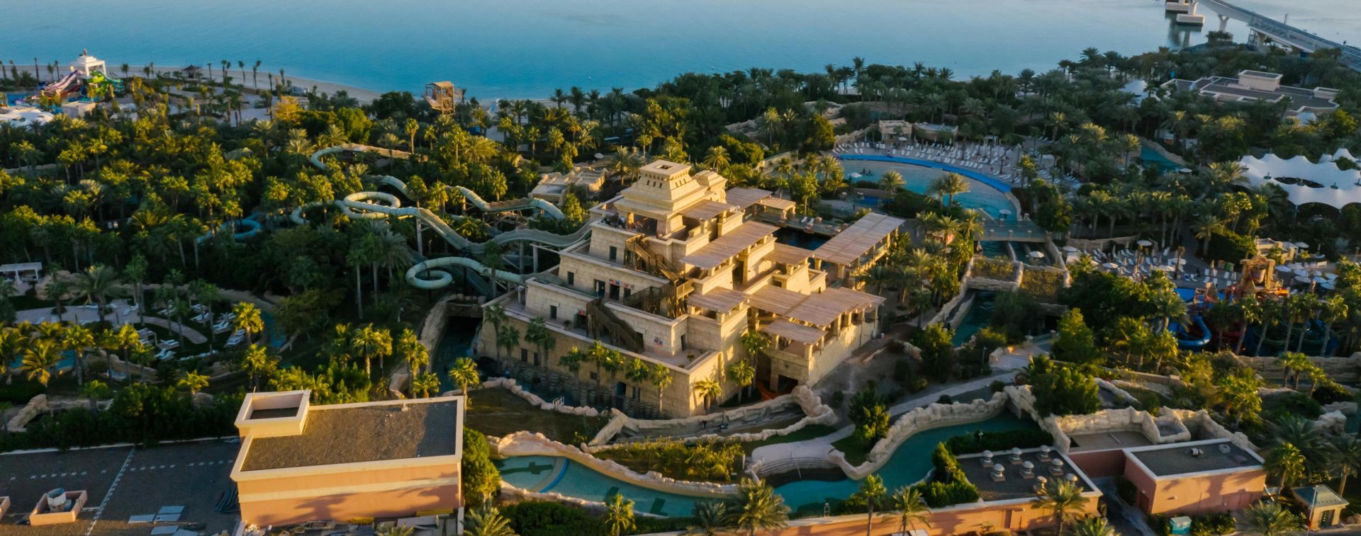 A breathtaking aerial shot of Palm Jumeirah with the Dubai skyline in the backdrop, featuring serene waters and lush greenery.